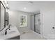 Bathroom featuring double vanity sinks, walk-in shower with glass doors, and natural light at 2509 Wesley Chapel Rd, Indian Trail, NC 28079