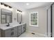 Bathroom featuring double vanity sinks, walk-in shower with glass doors, and natural light at 2509 Wesley Chapel Rd, Indian Trail, NC 28079