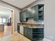 Stylish bar area with custom cabinets, granite countertop, stainless dishwasher, and tile backsplash at 3416 Windsor Dr, Charlotte, NC 28209