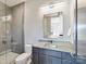 Bathroom with gray tiled shower, vanity with solid surface counter, and rectangular mirror with accent lighting at 3416 Windsor Dr, Charlotte, NC 28209