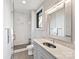 Bathroom with tiled shower, vanity with solid surface counter, rectangular mirror with accent lighting, and window at 3416 Windsor Dr, Charlotte, NC 28209