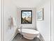 Elegant bathroom featuring a standalone soaking tub, heated towel rack, modern fixtures, and a serene window view at 3416 Windsor Dr, Charlotte, NC 28209
