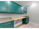 Functional laundry room with teal cabinets, countertop space, and practical design at 3416 Windsor Dr, Charlotte, NC 28209