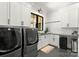 Bright laundry room with white cabinets, subway tile backsplash, modern appliances, and black framed window at 406 Morrison Farm Rd, Troutman, NC 28166