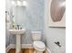Charming powder room with pedestal sink, patterned wallpaper, and modern fixtures at 408 Old Town Village Rd, Waxhaw, NC 28173