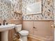 Chic half bathroom with floral wallpaper, pedestal sink, modern fixtures, and wood-look flooring, creating a stylish space at 408 Old Town Village Rd, Waxhaw, NC 28173