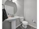 Pedestal sink, mirror, and toilet in half-bathroom with gray walls and gray flooring at 4631 Christina Ct, Gastonia, NC 28056