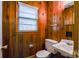 Cozy bathroom featuring wood paneling, a toilet, and a sink at 5536 Seacroft Rd, Charlotte, NC 28210