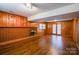 Spacious living room with wood paneling, a brick fireplace, laminate flooring, and sliding glass doors at 5536 Seacroft Rd, Charlotte, NC 28210