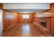 Spacious living room with wood paneling, a brick fireplace, and laminate flooring at 5536 Seacroft Rd, Charlotte, NC 28210