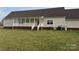 Spacious backyard featuring a well-maintained lawn, a covered porch with white railing, and a back entrance to the home at 6795 Jones Rd, Salisbury, NC 28147