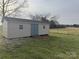New neutral colored storage shed featuring barn doors and a ramp on a green lawn at 6795 Jones Rd, Salisbury, NC 28147