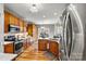 This kitchen has stainless steel appliances, wood cabinets, and a view through a sliding door to an outdoor dining table at 7331 Sedgebrook W Dr, Stanley, NC 28164