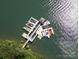 Aerial view of a private boat dock on a lake with multiple boat slips and a covered seating area at 7794 Live Oaks Dr, Denver, NC 28037