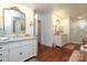 Elegant bathroom with white cabinetry, marble countertops, wood floors and a large gold-trimmed mirror at 7794 Live Oaks Dr, Denver, NC 28037