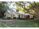 Inviting home exterior with string lights, covered porch, lush greenery and mature trees at 7794 Live Oaks Dr, Denver, NC 28037
