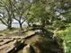 Scenic view of a tranquil pond with rock borders, surrounded by mature trees and landscaping at 7794 Live Oaks Dr, Denver, NC 28037