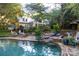 Beautiful pool area featuring stone accents, lush landscaping and mature trees, perfect for relaxing and entertaining at 7794 Live Oaks Dr, Denver, NC 28037