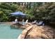 Poolside seating area with cushioned chairs and stone patio next to the water at 7794 Live Oaks Dr, Denver, NC 28037