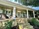 Inviting covered porch with stone accents, offering a relaxing outdoor space with seating and pleasant ambiance at 7794 Live Oaks Dr, Denver, NC 28037
