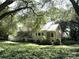 Quaint home with a metal roof, picket fence, well-manicured lawn, and mature trees at 7794 Live Oaks Dr, Denver, NC 28037