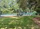 Fenced tennis court surrounded by a lush lawn and mature trees offering a private recreational space at 7794 Live Oaks Dr, Denver, NC 28037