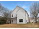 Back of a modern two-story home with a white exterior, green grass, and several bare trees at 9507 Weston Woods Ln, Charlotte, NC 28216