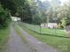 Long gravel driveway leading to multiple mobile homes on a tree covered lot, needs TLC at 1000 Jl Tyson Dr, Gastonia, NC 28056