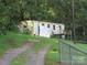 View of mobile home with porch, light siding, brown roof, and fenced yard, needs TLC at 1000 Jl Tyson Dr, Gastonia, NC 28056