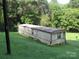 View of mobile home on a sloped lot with a brown roof, light siding, and some TLC at 1000 Jl Tyson Dr, Gastonia, NC 28056