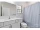 Bright, minimalist bathroom with a single sink vanity and shower with curtain at 1129 Doveridge St, Charlotte, NC 28273