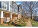 A row of inviting townhomes with brick bases and blue siding lines a sidewalk with beautiful landscaping and trees at 1525 Walnut View Dr, Charlotte, NC 28208