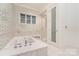 Spa-like main bathroom featuring a soaking tub, glass enclosed shower, and mosaic tile at 1665 Sterling Rd, Charlotte, NC 28209