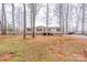 Lawn features a beige home with a wooden porch, gravel driveway, and mature trees at 1795 Kestrel Valley Ln, Catawba, NC 28609
