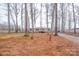 Lawn features a beige home with a wooden porch, gravel driveway, and mature trees at 1795 Kestrel Valley Ln, Catawba, NC 28609