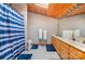 Bathroom with light wood cabinets, a skylight, and a shower with a blue striped curtain for added privacy at 190 Country Dr, Statesville, NC 28625