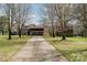 Long driveway leading up to a brick home with an attached three car garage surrounded by trees at 190 Country Dr, Statesville, NC 28625