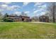 A brick home with a large front yard, detached garage, and three car garage with a blue sky at 190 Country Dr, Statesville, NC 28625