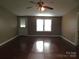 An open living room featuring wood laminate flooring, a ceiling fan, and natural light from large windows at 1909 E Lawyers Rd, Monroe, NC 28110