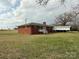 Exterior view featuring a brick home with white trim, a large yard, and covered parking at 2730 Medlin Rd, Monroe, NC 28112