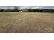 Large lot featuring an expansive grassy area, a small home, and mature trees in the background at 2730 Medlin Rd, Monroe, NC 28112