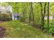 View of backyard featuring detached garage, green lawn, and surrounded by mature trees for privacy at 306 Ashby Dr, Davidson, NC 28036