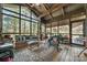 Relax in this cozy sunroom featuring rustic furnishings, a ceiling fan, a large window, and serene views of the surrounding woods at 32 Fairway Rdg, Lake Wylie, SC 29710