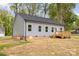 Light-gray vinyl home featuring a wooden deck and dark shingled roof surrounded by lush greenery at 409 Bost St, Kannapolis, NC 28081