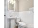 Compact powder room with white tiled walls, classic pedestal sink, and toilet at 4931 Galax Dr, Charlotte, NC 28213