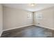 Cozy bedroom with gray wood flooring, neutral walls, and two bright windows at 4931 Galax Dr, Charlotte, NC 28213