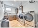 Modern laundry room with front loading washer and dryer, wooden cabinets, and light hardwood floors at 805 E 19Th St, Charlotte, NC 28205