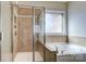 Bathroom with a glass enclosed shower and tub with stone tile surround at 8513 Garden View Dr, Charlotte, NC 28277