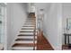 Hallway featuring hardwood floors, stairs with wood trim, and white walls at 8812 Provence Village Ln, Charlotte, NC 28226