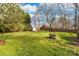 Large backyard has green grass, mature trees, fire pit, and shed at 1025 Hunter Valley Rd, Shelby, NC 28150